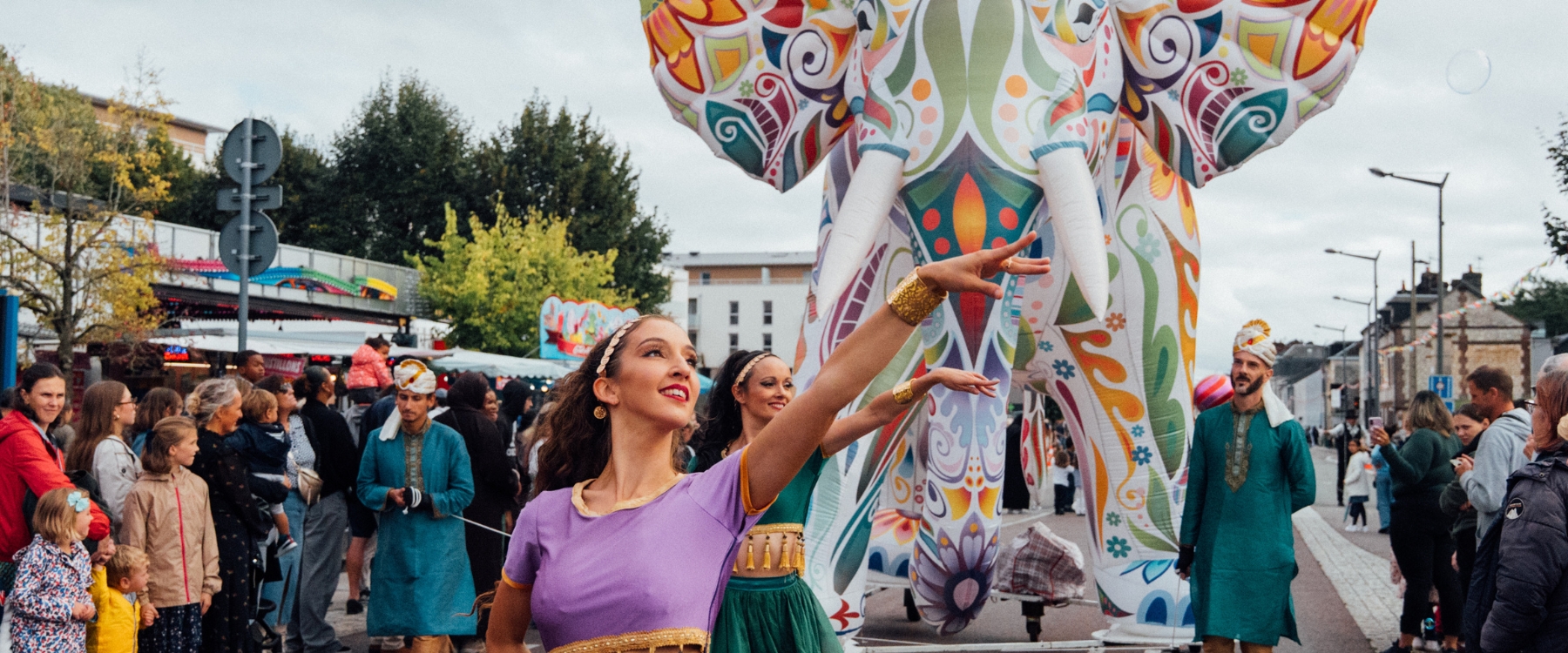 "Éléphant géant coloré lors déambulation Rêve Hindou Bollywood" "Danseurs en costumes éclatants de la déambulation Rêve Hindou" "Déambulation festive aux couleurs de Bollywood avec artistes illuminés"